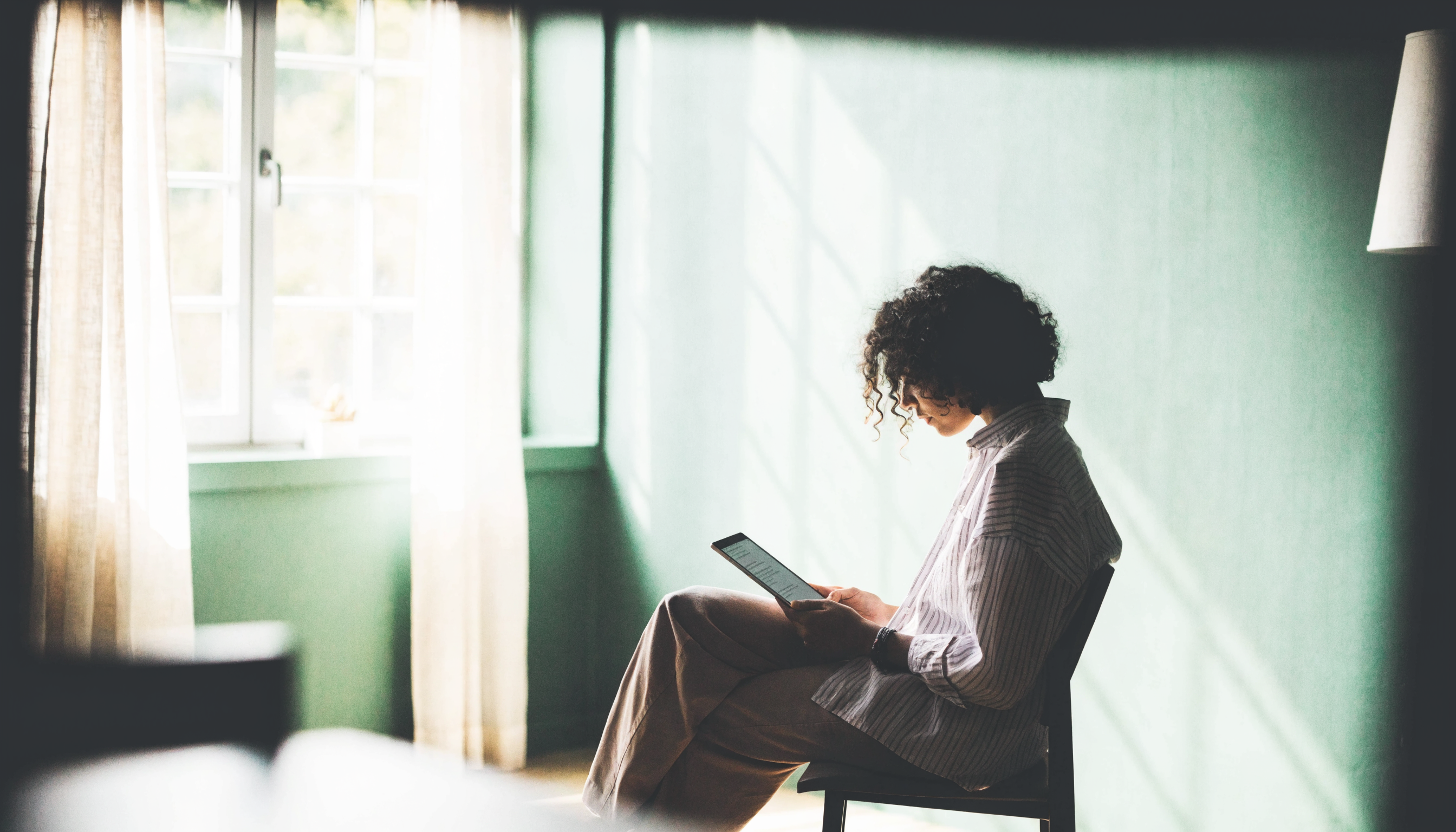 Person reading a digital guide by a window in calm natural light
